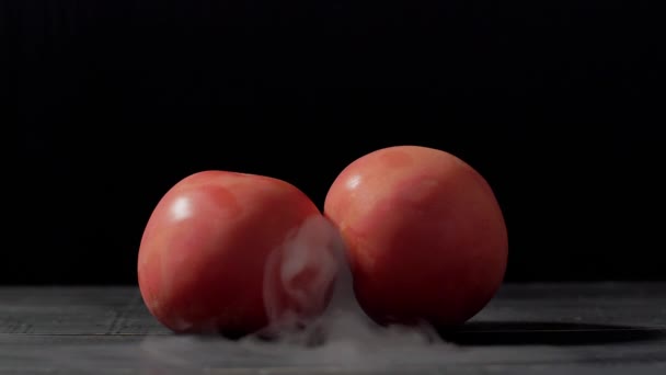 Humo en cámara lenta sobre fondo negro y tomates — Vídeos de Stock