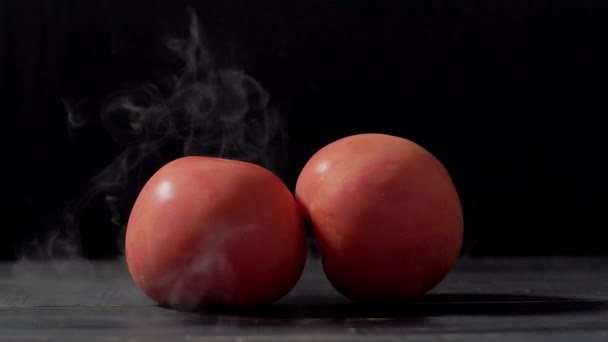 Humo en cámara lenta sobre fondo negro y tomates — Vídeo de stock