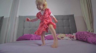 Yatakta kırmızı elbise atlama ile mutlu sarışın kız