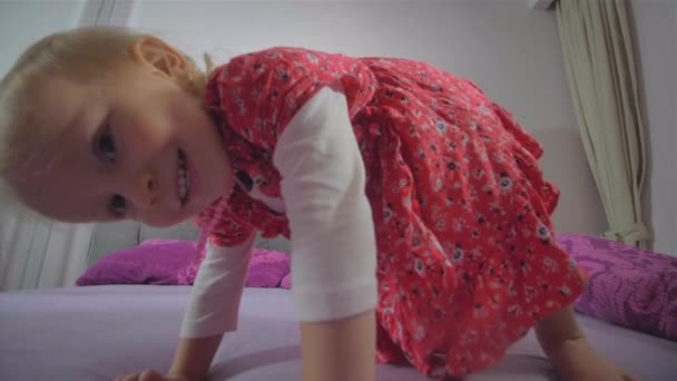 Chica rubia feliz con vestido rojo saltando en la cama — Vídeos de Stock