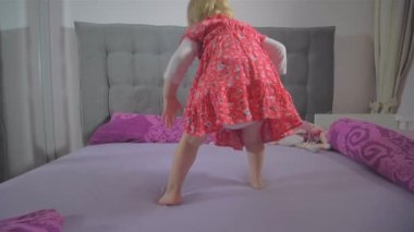 Yatakta kırmızı elbise atlama ile mutlu sarışın kız