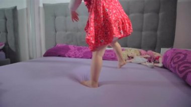 Yatakta kırmızı elbise atlama ile mutlu sarışın kız