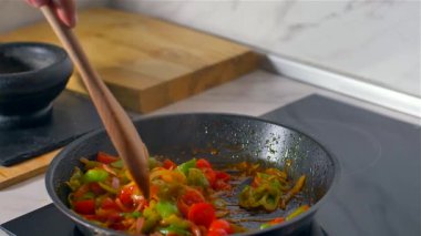 Aşçı tahta kaşıkla tavada sebze karıştırır. Yavaş çekim