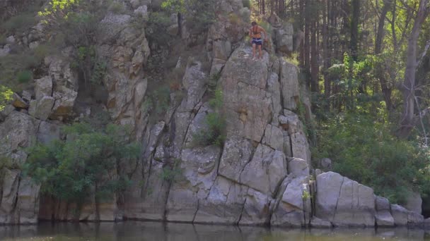 En pojke hoppade in i floden från de höga klipporna — Stockvideo