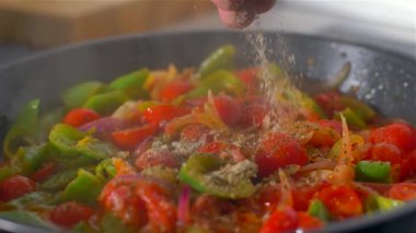 Aşçı tatlar bir tavada sebze ve tuz serpilir.