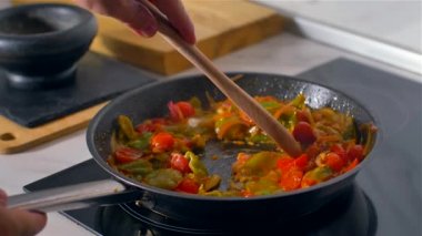Aşçı tahta kaşıkla tavada sebze karıştırır. Yavaş çekim
