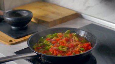 Aşçı bir harç içinde baharat öğütür ve tatlar tavada sebze.