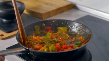 Aşçı tahta kaşıkla tavada sebze karıştırır. Yavaş çekim