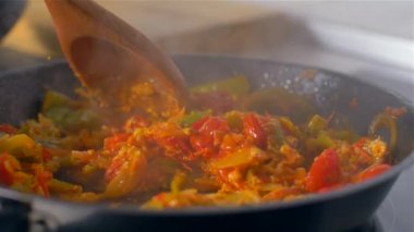 Aşçı tahta kaşıkla tavada sebze karıştırır. Yavaş çekim
