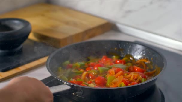 Chef trabalhando na cozinha, legumes coloridos misturados são assados em uma panela . — Vídeo de Stock