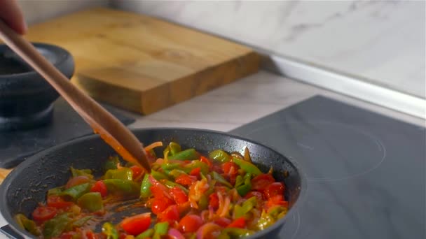 Der Koch rührt das Gemüse in der Pfanne mit einem Holzlöffel um. Zeitlupe — Stockvideo