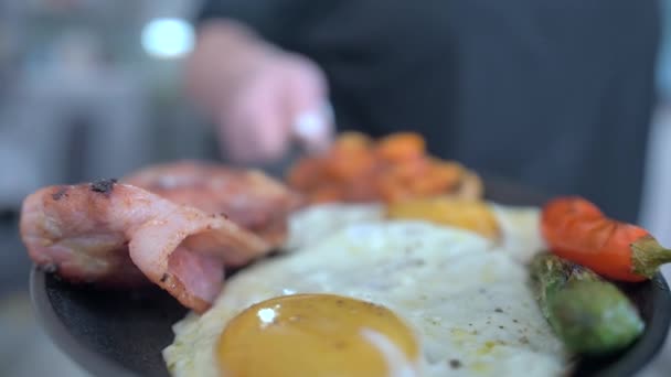 Завтрак, яичница с сосисками, зеленая фасоль, помидоры. Подача на деревянном столе в ресторане. Крупный план . — стоковое видео