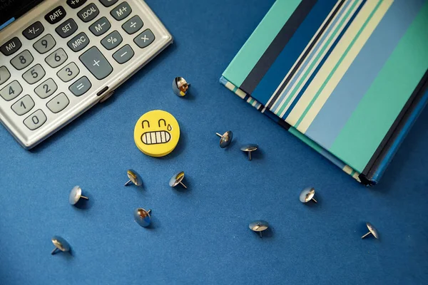 stationery on a blue background,  an eraser, a gray calculator, notebook. top view  pushpins. top view