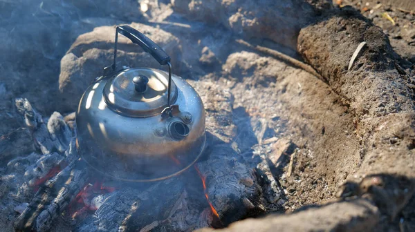 Dışarıdaki kamp ateşi geleneksel kaynayan çaydanlıkla pişiriliyor.