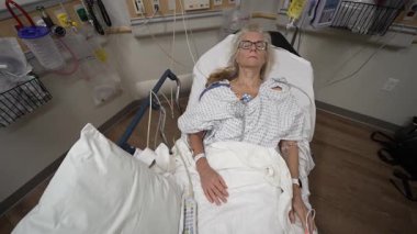 Winchester, VA, ABD - 09 03 2025: Olgun bir kadın acil serviste bir hastane yatağında dinleniyor. Sessizce yatarken sağlık sorunları için tedavi görüyor ve izliyor gibi görünüyor..