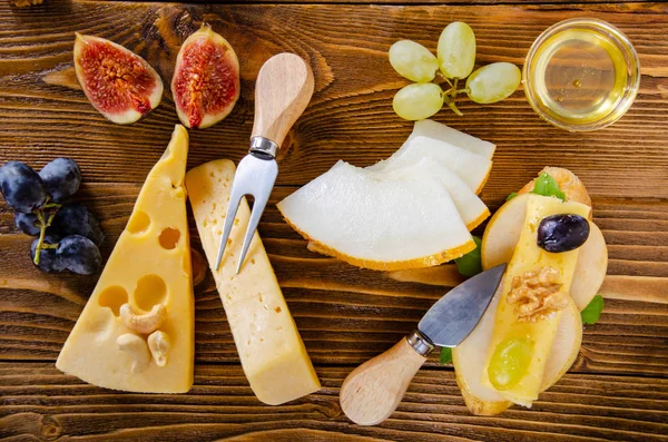 Cheese, fruit and honey. Tool for cheese. Wooden table. Top view.
