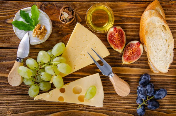 Cheese, fruit and honey. Tool for cheese. Wooden table. Top view.