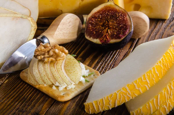 Cheese, bruschetta, fruit and honey. Tool for cheese. Wooden table.