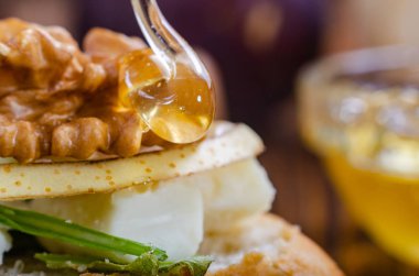 Bruschetta peynir, meyve ve fındık ile ahşap bir masa üzerinde bal ile drizzled.