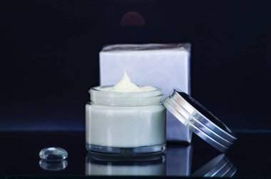 kavanoz krem, cam masa bir kutuyu açın. Siyah arka plan.