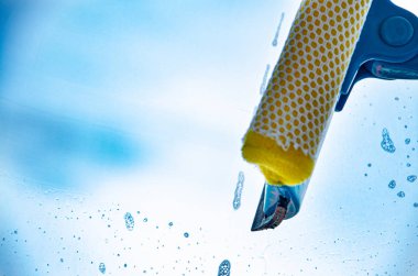 Cam ve mavi gökyüzünü temizleyen bir paspas ile pencere temizliği