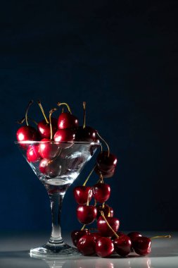 Dolu bardaktan dökülen kirazlı kompozisyon. Siyah arkaplan