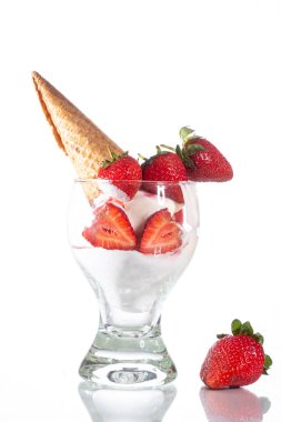 Cam bir masanın üzerinde beyaz çilekli dondurma ve waffle külahı. Beyaz arkaplan.