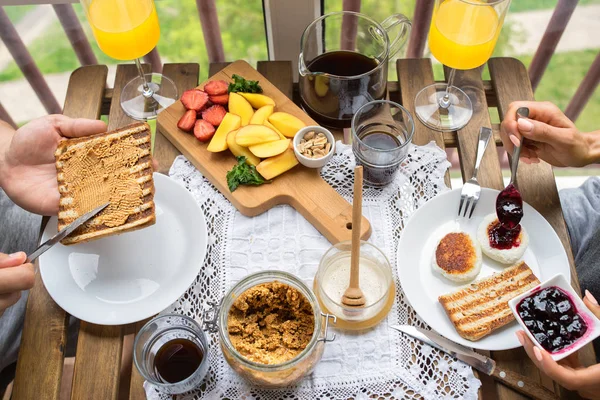 Pareja desayunando en el balcón. Desayuno con tostadas, mermelada y café — Foto de Stock