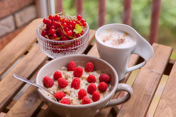 Здоровый завтрак: овсянка со свежими ягодами в миске с чашкой кофе — стоковое фото
