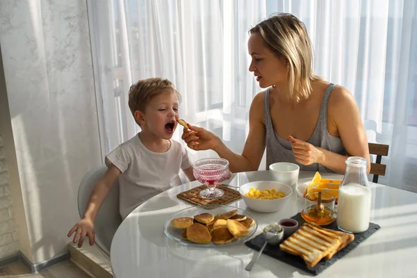 Мать кормит ребёнка завтраком. Яркое солнечное утро . — стоковое фото
