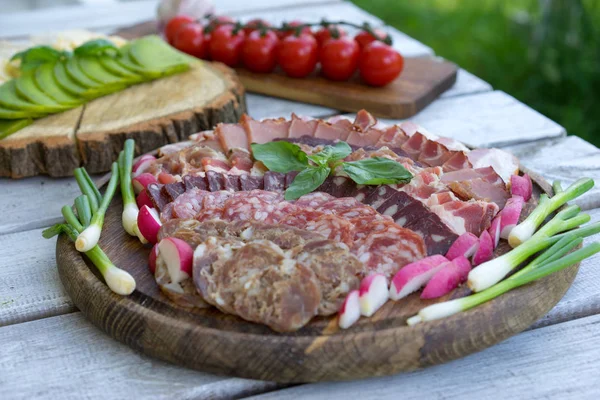 Lezzetli salamlı yemek tepsisi, dilimlenmiş jambon, sosis, domates, salata ve sebze parçaları - seçmeli et tabağı - sosis kesmek ve bir kutlama masasında pişirilmiş et. — Stok fotoğraf