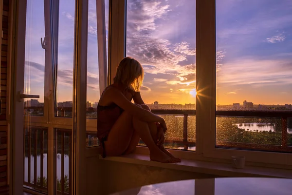 Femme le matin. Belle femme sexy avec un corps soigné regarde le lever du soleil assis sur la fenêtre dans sa maison et avoir une matinée confortable parfaite avec une tasse de café . — Photo