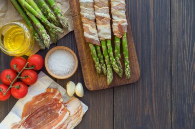 Parma jambonu bir kesme tahtası üzerinde sarılı taze organik kuşkonmaz