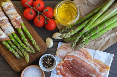 Parma jambonu bir kesme tahtası üzerinde sarılı taze organik kuşkonmaz