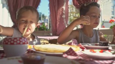 İki erkek balkonda kahvaltıda krep yiyor