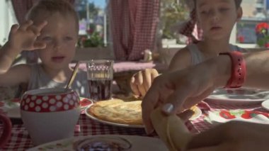 İki erkek balkonda kahvaltıda krep yiyor