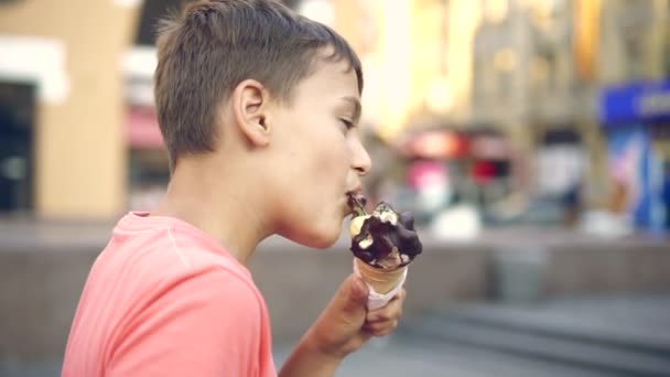Young boy licking ice cream in a cone during summertime — Stock Video