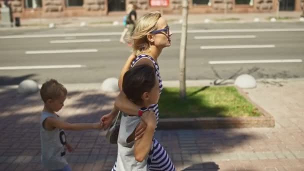 Мать и двое сыновей идут по улице — стоковое видео