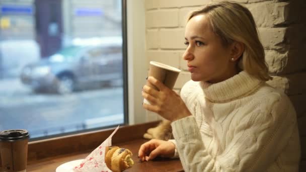Giovane donna che fa colazione alla francese con caffè e croissant seduta nel caffè — Video Stock