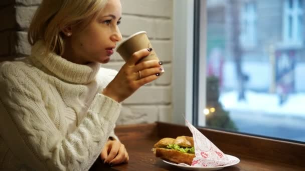 Mladá žena s francouzskou snídani s kávou a croissantem sedí v kavárně — Stock video