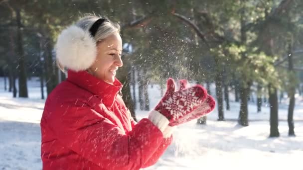 Flicka i rött blåser i handflatorna av snön i den varma solnedgången solen — Stockvideo