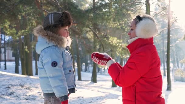 Dívka v červeném fouká v dlaních na sněhu v západ sluníčka — Stock video