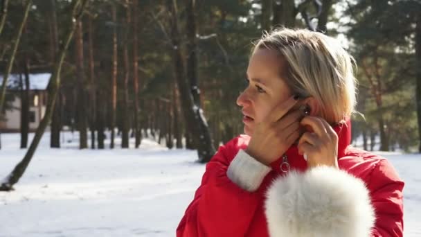 Jovem mulher atraente usar fones de ouvido sem fio no parque de inverno neve — Vídeo de Stock