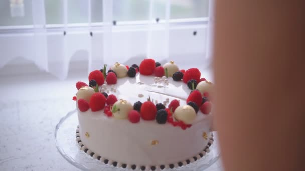 Женщина режет торт, украшенный ягодами — стоковое видео