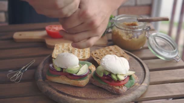 A man making sandwiches with poached egg — Stock Video