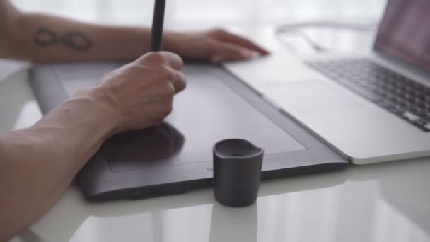 Женская рука с графическим планшетом на столе крупным планом. Женщина, работающая с ноутбуком дома — стоковое видео