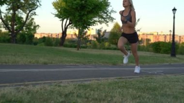 Genç çekici atletik kadın ağır çekimde gün batımında Park'ta jogging