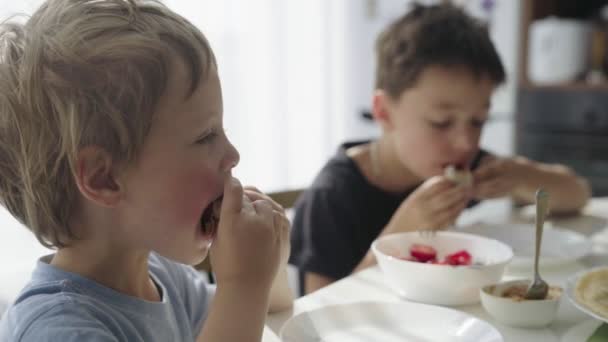 De jongens pannenkoeken met aardbeien in buis oprollen. Jongens pannenkoeken eten. — Stockvideo