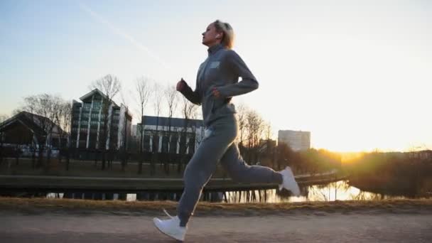 Mujer en forma corriendo en la ciudad en la hermosa salida del sol — Vídeo de stock