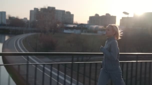 Fitte Frau joggt bei schönem Sonnenaufgang in der Stadt — Stockvideo